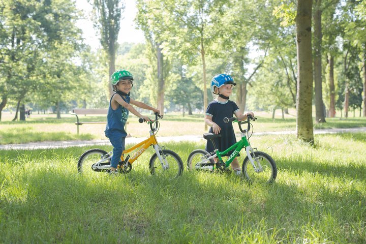 Kinder mit ihren woom Fahrrädern in der Wiese