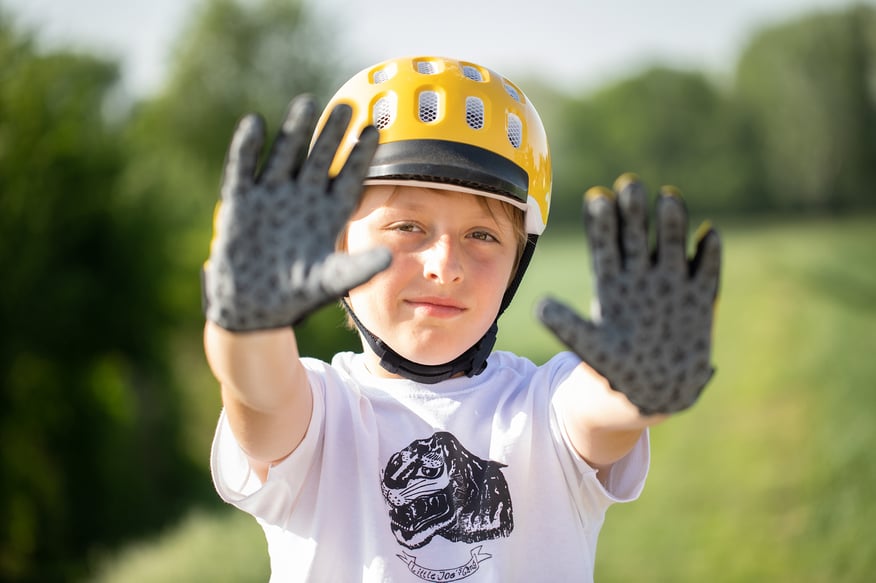 Kind mit woom Helm und Fahrradhandschuhen